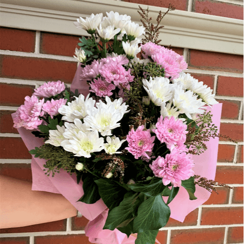 Pink and white chrysanthemum flowers wrapped together with ivy berry and wax flowers.