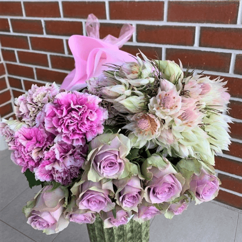 Purple carnations and roses wrapped together with blushing brides.