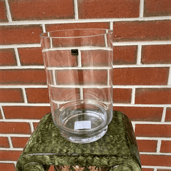 Empty clear glass vase sitting on a stand.