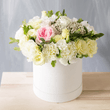 Arrangement of pastel flowers in a white hat box. Available for online order.