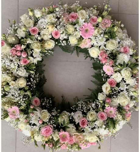 Pink and white flowers funeral flowers wreath sitting on the floor.