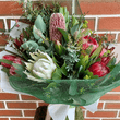 Assortment of native flowers wrapped in white paper and green net.