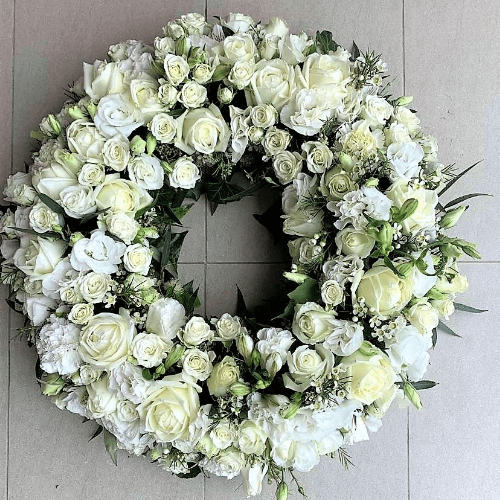 Large white flowers wreath sitting on the floor.