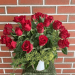 Red roses and foliage arranged in a white ceramic container