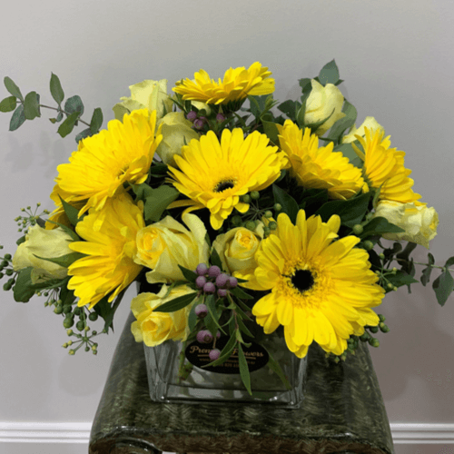 Glass cube with yellow roses and gerberas