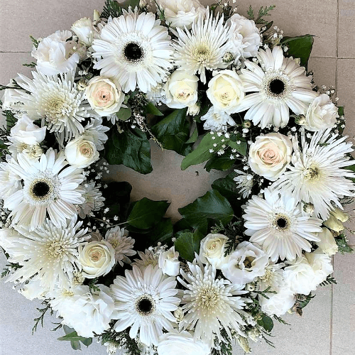 White flowers funeral wreath sitting on the ground.