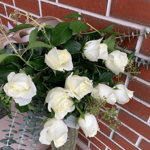 White roses and greenery wrapped in hessian. 