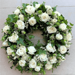 White roses funeral wreath sitting on the ground.