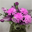 Pink and purple flowers arranged in a green ceramic container.