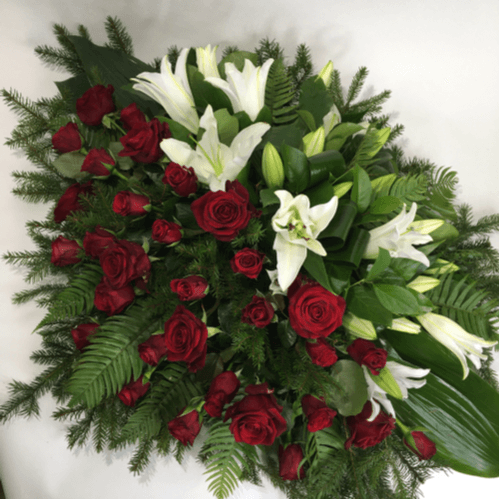 Funeral casket spray consisting of white lilies on one side and red roses on the other side.