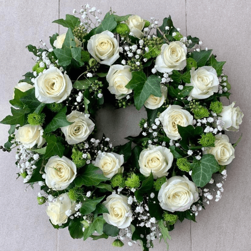 White roses and greenery wreath sitting on the floor