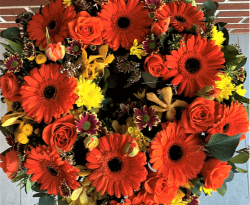 Funeral Flower wreath with orange gerberas, roses, tulips and yellow chrysanthemums.