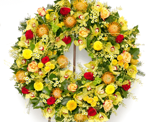 Yellow and orange funeral flower wreath sitting on the ground.